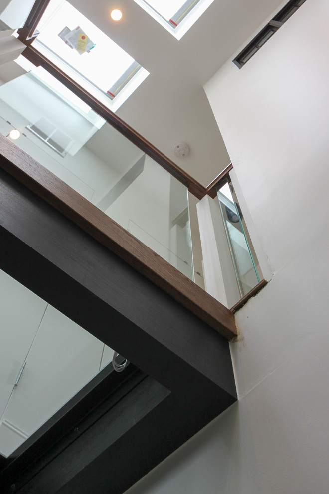 Cette image montre un très grand escalier sans contremarche flottant design avec des marches en verre et un garde-corps en verre.