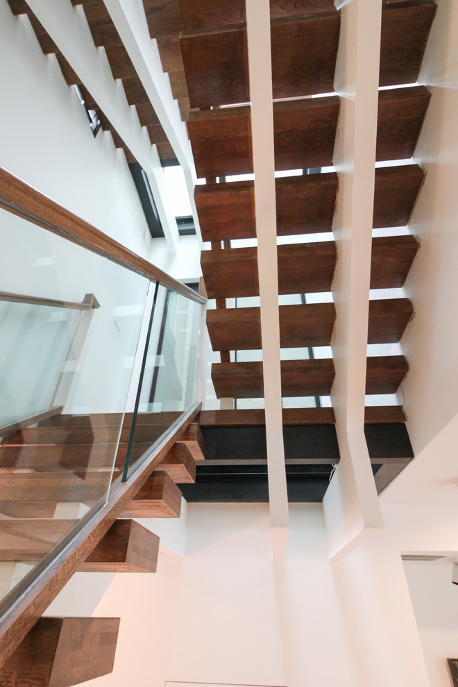 Exempel på en mycket stor modern flytande trappa i glas, med öppna sättsteg och räcke i glas