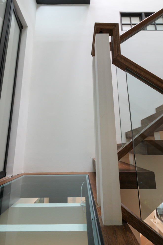 Cette photo montre un très grand escalier sans contremarche flottant tendance avec des marches en verre et un garde-corps en verre.