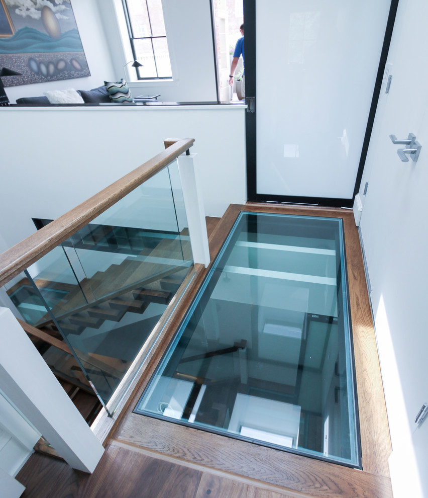 На фото: огромная лестница на больцах в современном стиле с стеклянными ступенями и стеклянными перилами без подступенок с