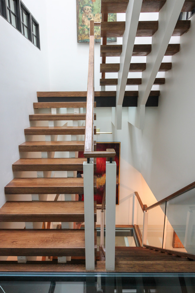На фото: огромная лестница на больцах в современном стиле с стеклянными ступенями и стеклянными перилами без подступенок