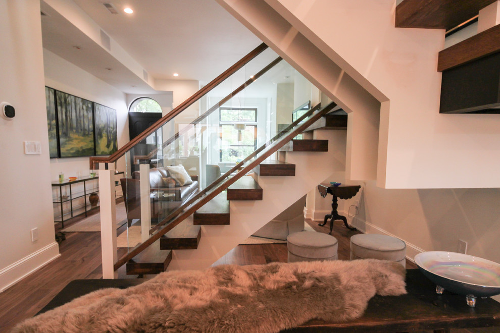 Стильный дизайн: огромная лестница на больцах в современном стиле с стеклянными ступенями и стеклянными перилами без подступенок - последний тренд