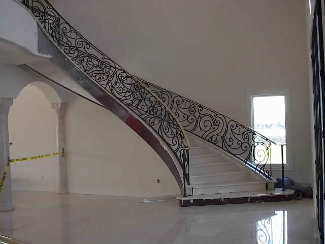Foto di una grande scala curva stile shabby con pedata in legno, alzata in legno e parapetto in metallo