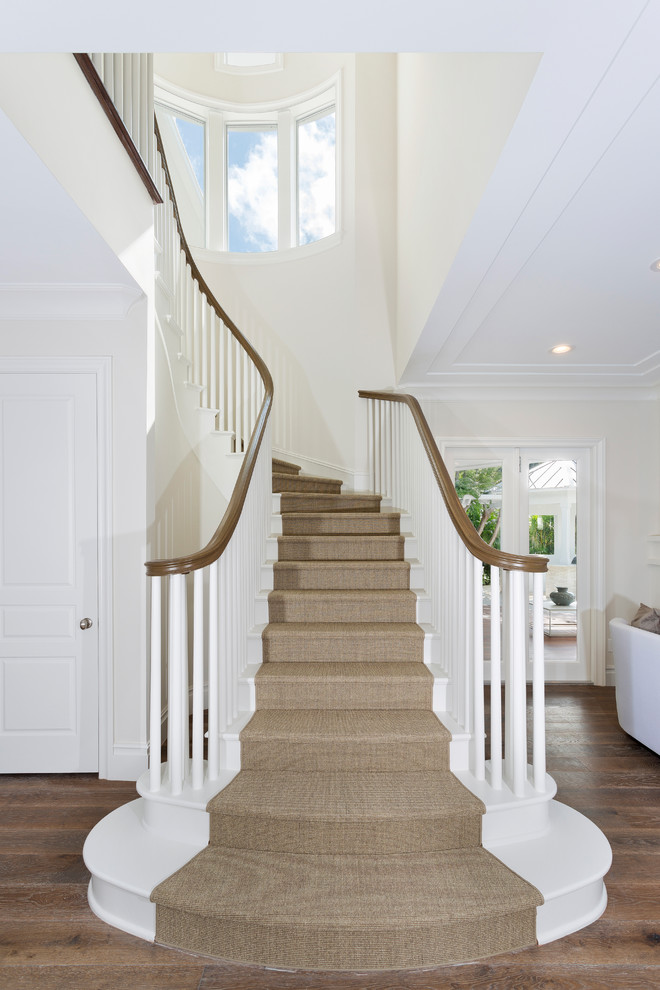 На фото: винтовая деревянная лестница среднего размера в морском стиле с ступенями с ковровым покрытием и деревянными перилами с