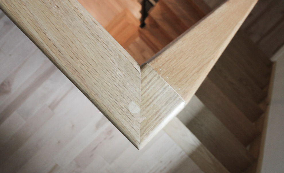 Immagine di una grande scala a rampa dritta minimalista con pedata in legno, alzata in legno e parapetto in materiali misti
