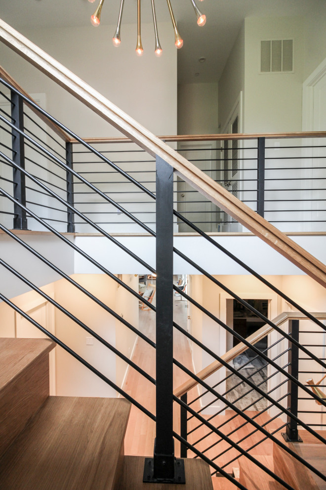 Cette image montre un grand escalier droit minimaliste avec des marches en bois, des contremarches en bois et un garde-corps en matériaux mixtes.