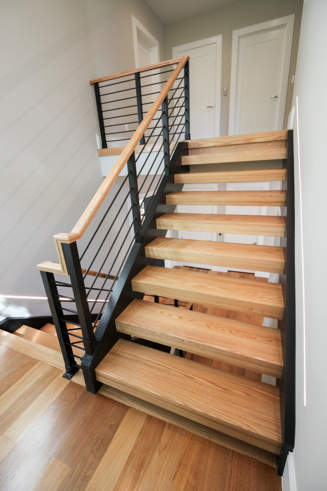 Пример оригинального дизайна: большая п-образная лестница в современном стиле с деревянными ступенями и перилами из смешанных материалов