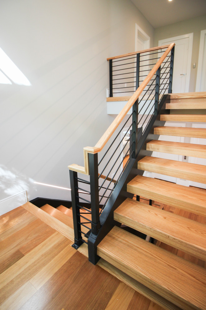 На фото: большая п-образная лестница в современном стиле с деревянными ступенями и перилами из смешанных материалов с