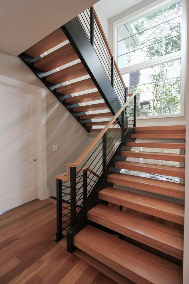 Cette image montre un grand escalier design en U avec des marches en bois et un garde-corps en matériaux mixtes.