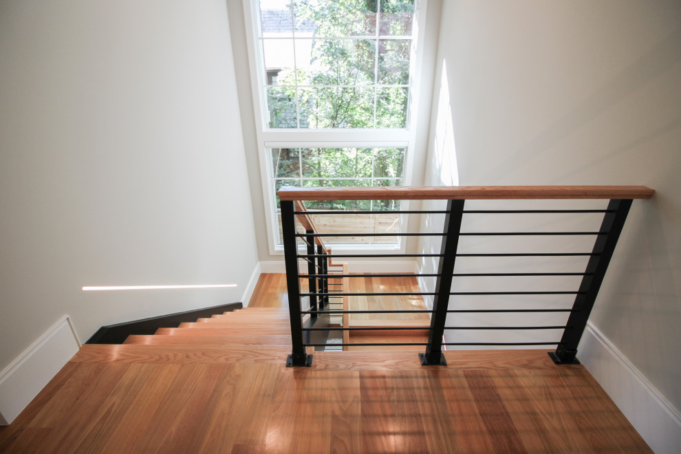 Réalisation d'un grand escalier design en U avec des marches en bois et un garde-corps en matériaux mixtes.