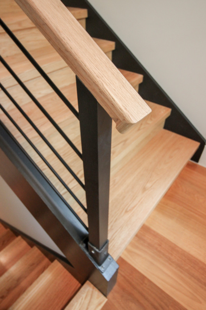 Exemple d'un grand escalier tendance en U avec des marches en bois et un garde-corps en matériaux mixtes.