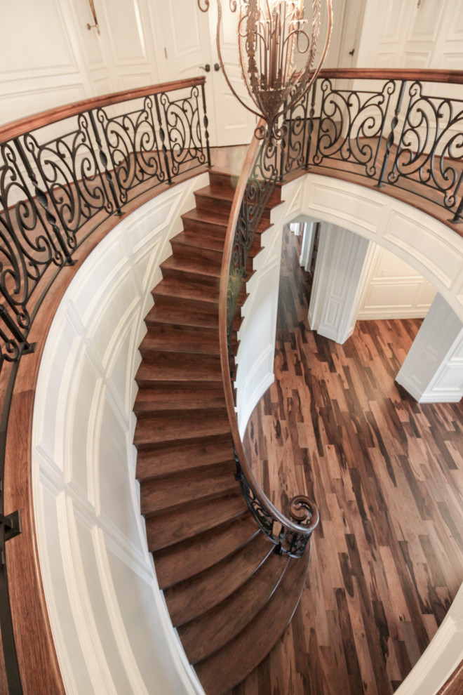 Стильный дизайн: большая изогнутая деревянная лестница в стиле фьюжн с деревянными ступенями и перилами из смешанных материалов - последний тренд