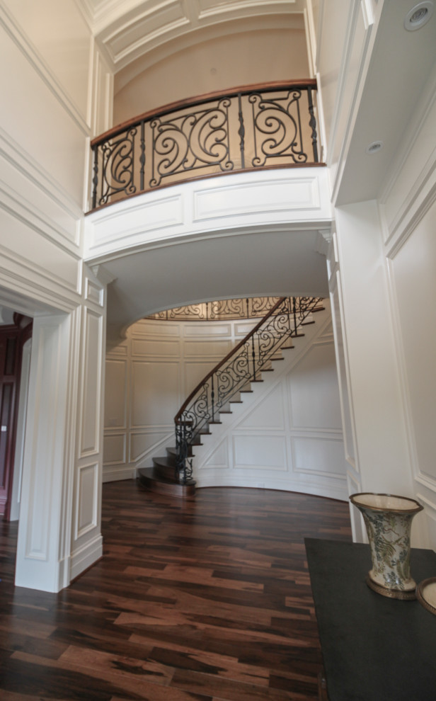 Пример оригинального дизайна: большая изогнутая деревянная лестница в стиле фьюжн с деревянными ступенями и перилами из смешанных материалов