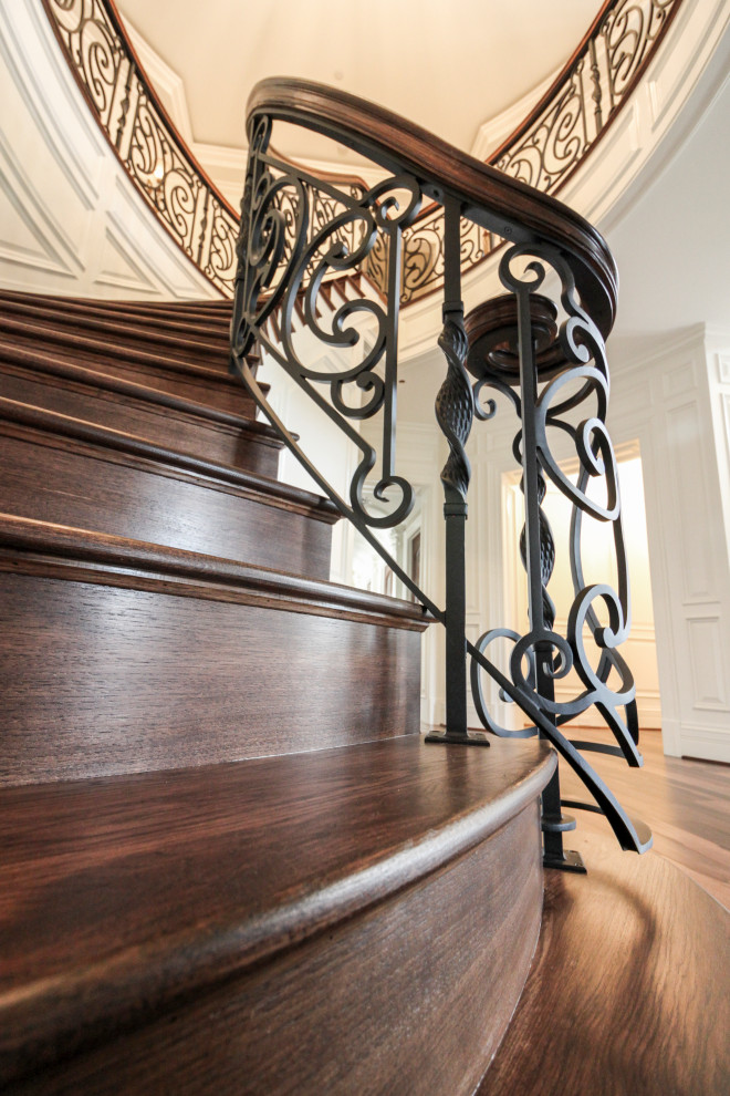 Diseño de escalera curva ecléctica grande con escalones de madera, contrahuellas de madera y barandilla de varios materiales