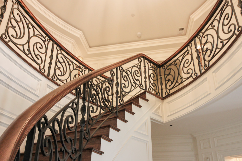 Стильный дизайн: большая изогнутая деревянная лестница в стиле фьюжн с деревянными ступенями и перилами из смешанных материалов - последний тренд