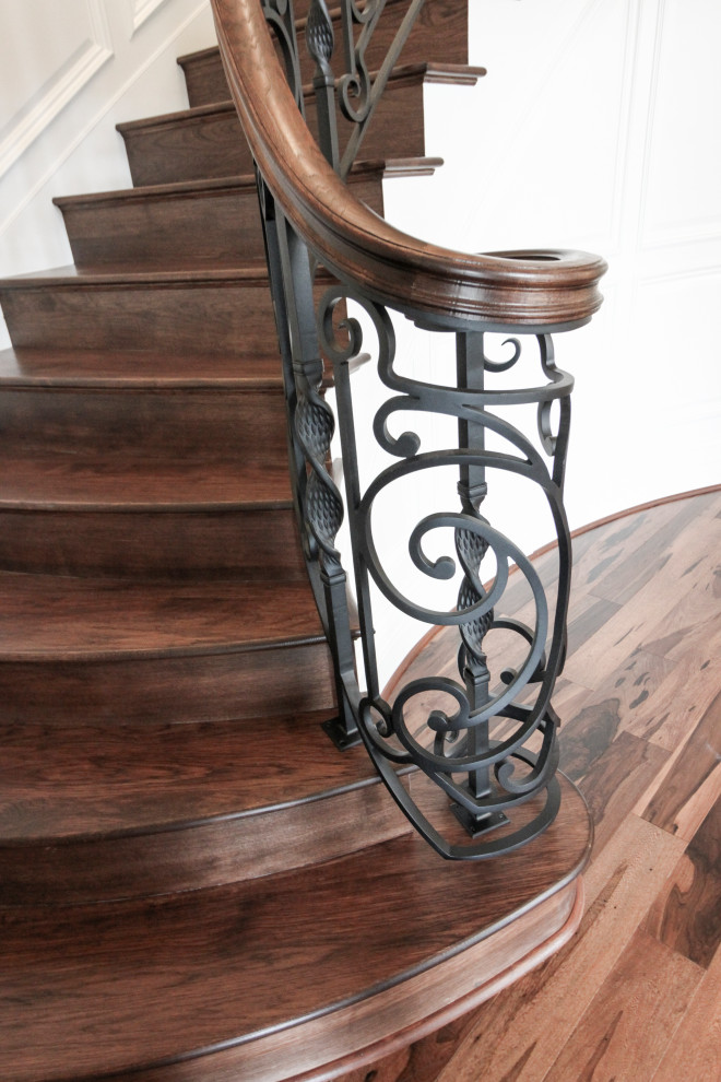 Aménagement d'un grand escalier courbe éclectique avec des marches en bois, des contremarches en bois et un garde-corps en matériaux mixtes.