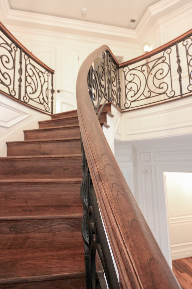Ejemplo de escalera curva ecléctica grande con escalones de madera, contrahuellas de madera y barandilla de varios materiales