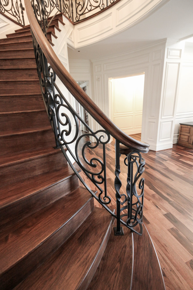 Ejemplo de escalera curva ecléctica grande con escalones de madera, contrahuellas de madera y barandilla de varios materiales
