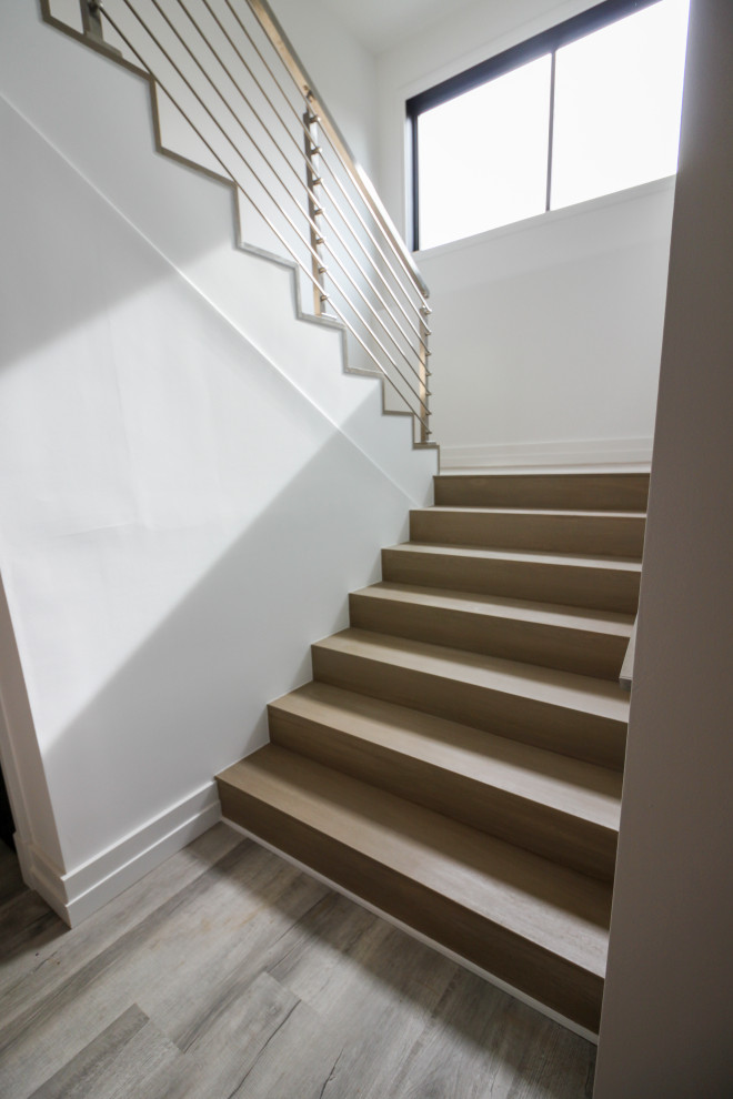 Imagen de escalera en U moderna de tamaño medio con escalones de madera, contrahuellas de madera y barandilla de metal