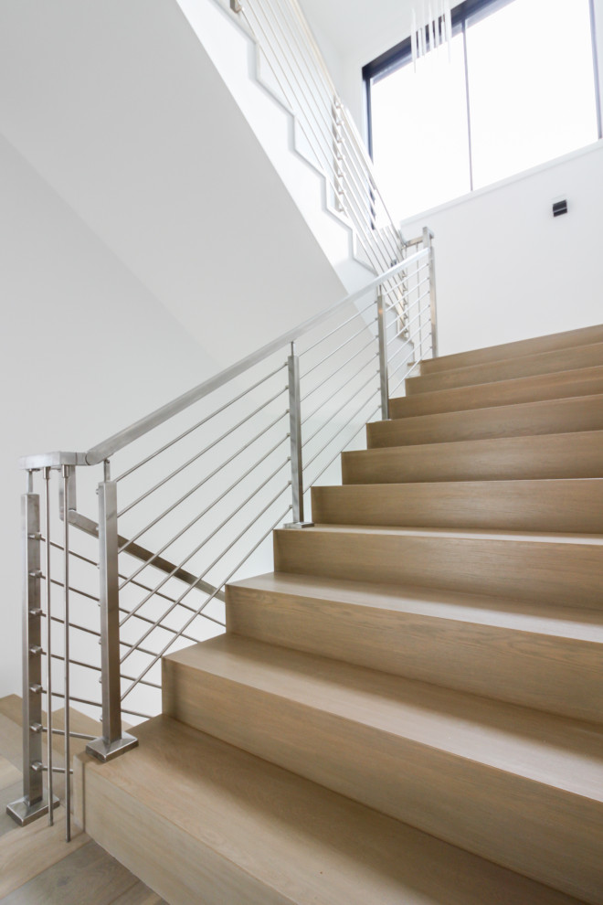 Réalisation d'un escalier minimaliste en U de taille moyenne avec des marches en bois, des contremarches en bois et un garde-corps en métal.