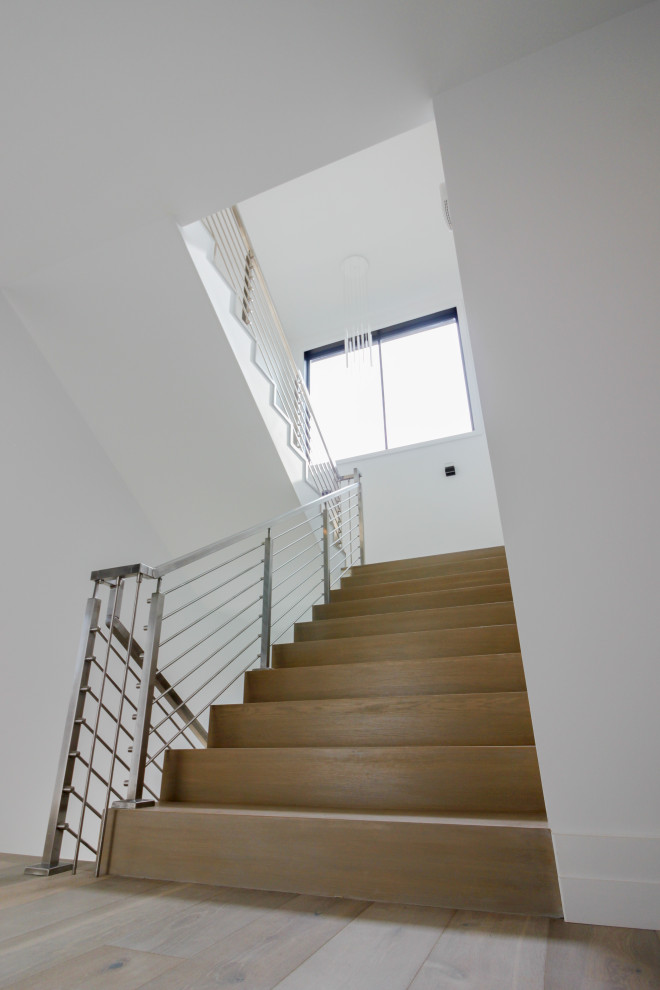Cette image montre un escalier minimaliste en U de taille moyenne avec des marches en bois, des contremarches en bois et un garde-corps en métal.