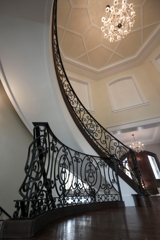 Diseño de escalera curva clásica renovada extra grande con escalones de madera, contrahuellas de madera y barandilla de metal