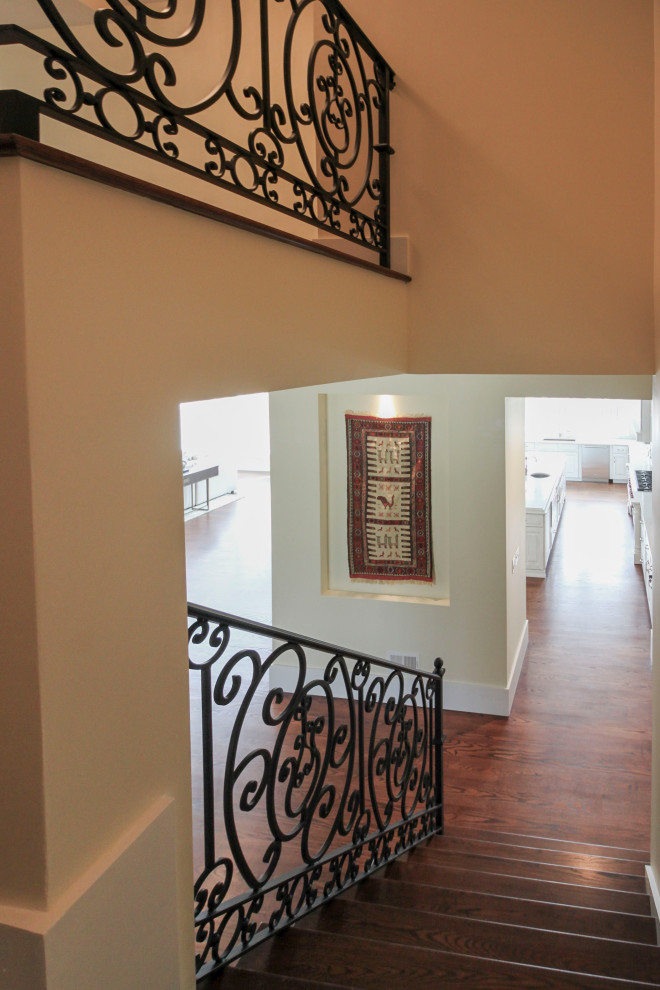 Diseño de escalera curva clásica renovada extra grande con escalones de madera, contrahuellas de madera y barandilla de metal