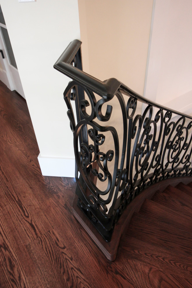 Imagen de escalera curva clásica renovada extra grande con escalones de madera, contrahuellas de madera y barandilla de metal