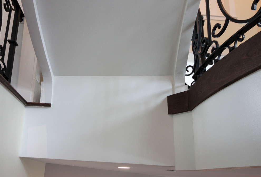 This is an example of an expansive traditional wood curved metal railing staircase in DC Metro with wood risers.