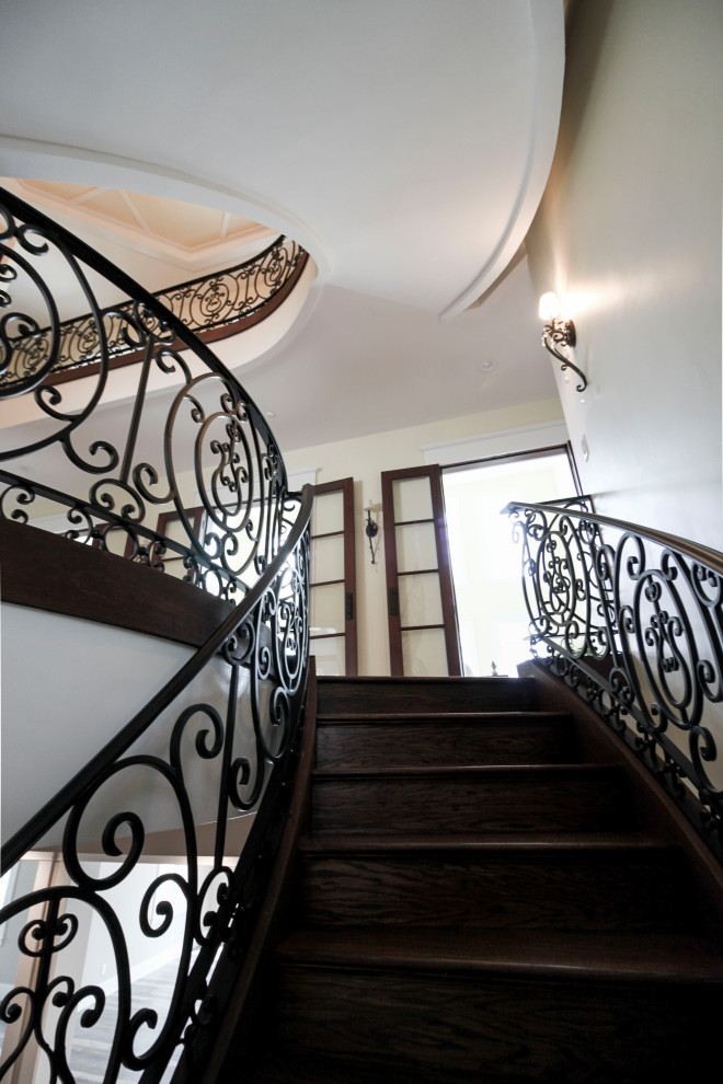Imagen de escalera curva tradicional renovada extra grande con escalones de madera, contrahuellas de madera y barandilla de metal