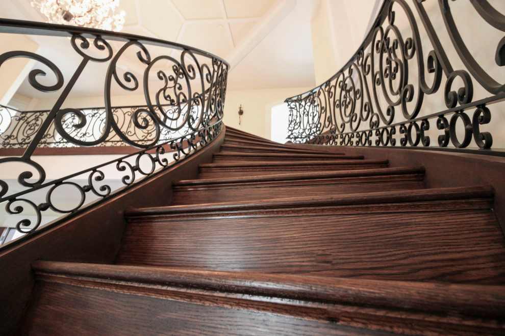 Ejemplo de escalera curva clásica renovada extra grande con escalones de madera, contrahuellas de madera y barandilla de metal