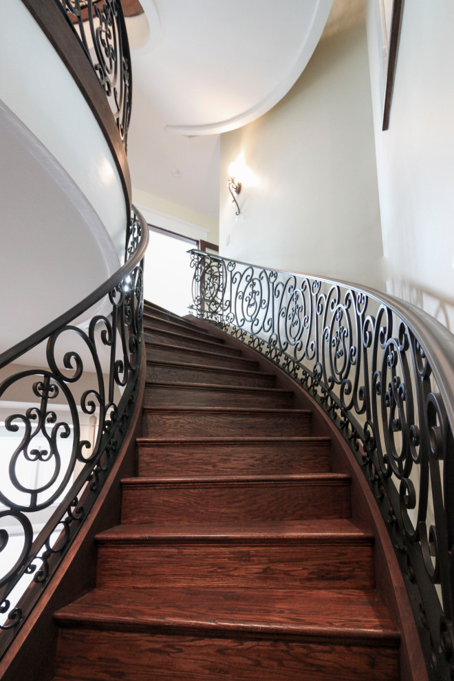 Imagen de escalera curva tradicional renovada extra grande con escalones de madera, contrahuellas de madera y barandilla de metal