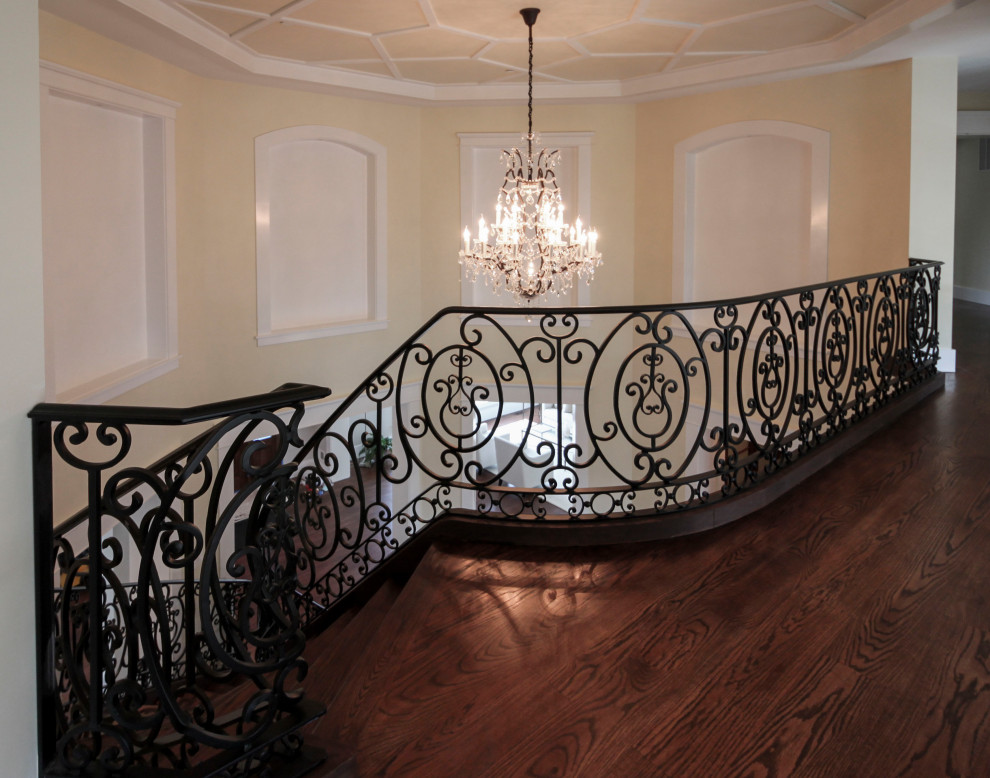 Photo of an expansive classic wood curved metal railing staircase in DC Metro with wood risers.
