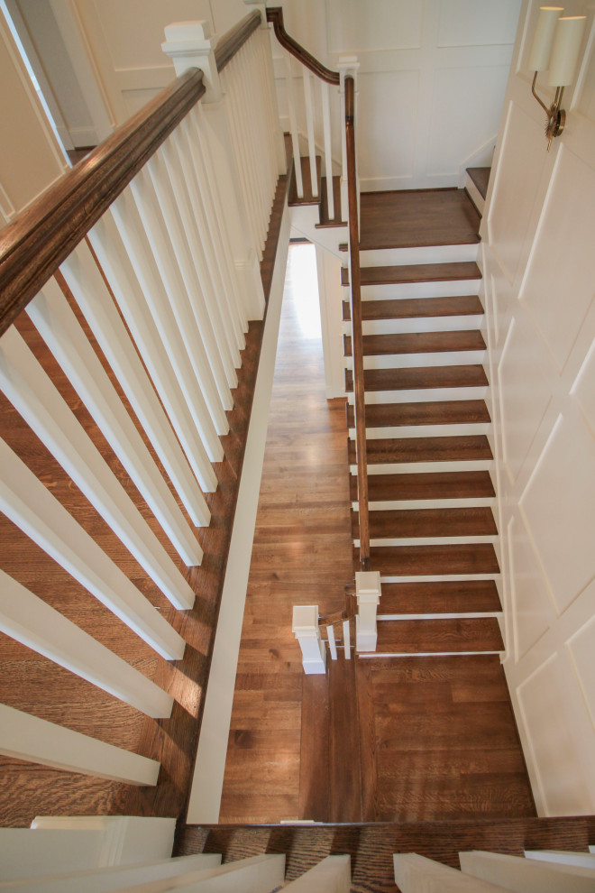 Imagen de escalera en U clásica renovada grande con escalones de madera, contrahuellas de madera, barandilla de madera y boiserie