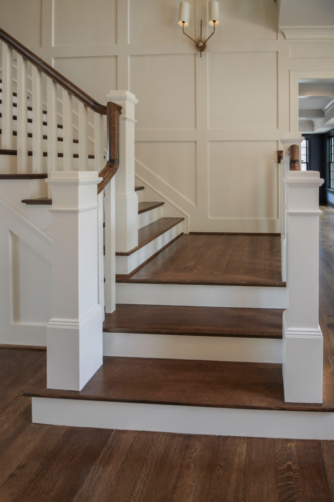 Ejemplo de escalera en U clásica renovada grande con escalones de madera, contrahuellas de madera, barandilla de madera y boiserie