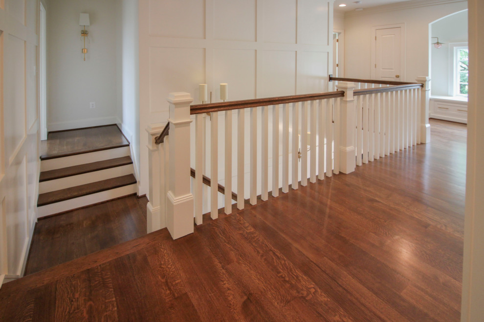 Photo of a large classic wood u-shaped wood railing staircase in DC Metro with wood risers and wainscoting.