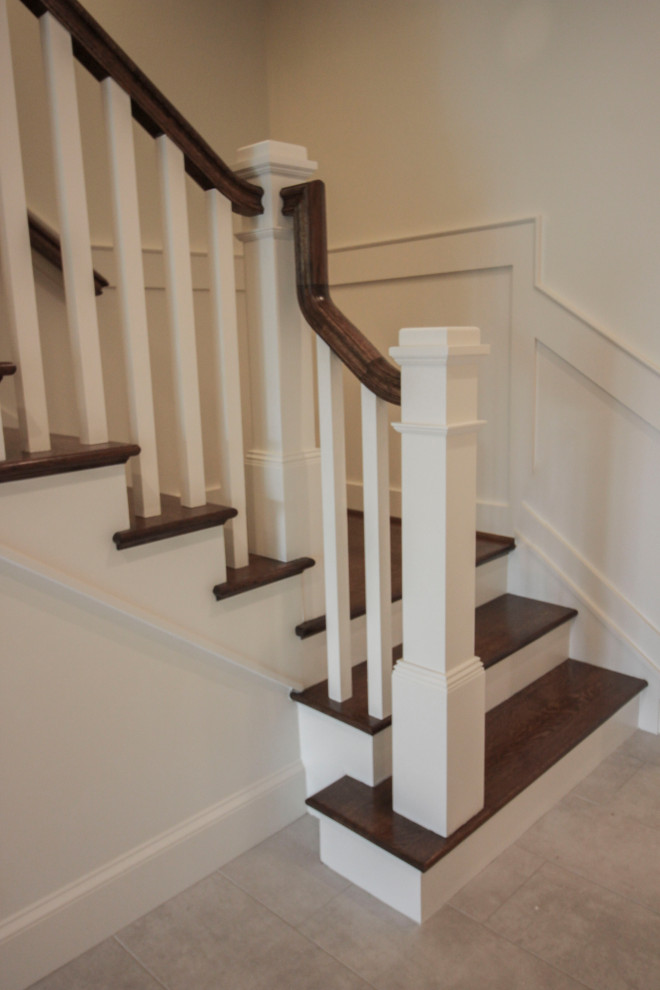 Стильный дизайн: большая п-образная деревянная лестница в стиле неоклассика (современная классика) с деревянными ступенями, деревянными перилами и панелями на стенах - последний тренд