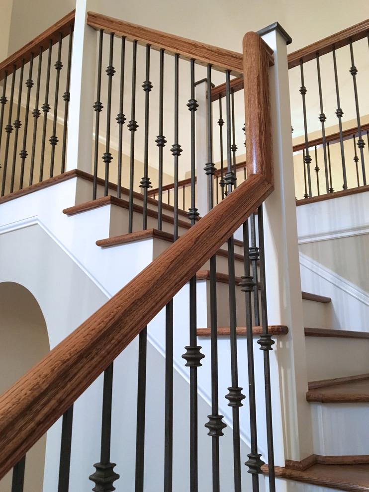На фото: большая угловая лестница в классическом стиле с деревянными ступенями, крашенными деревянными подступенками и перилами из смешанных материалов