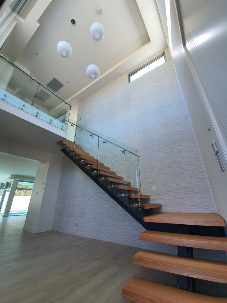 Cette photo montre un escalier sans contremarche tendance en L de taille moyenne avec des marches en bois et un garde-corps en verre.