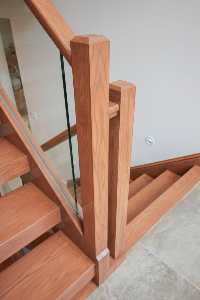 Стильный дизайн: лестница на больцах, среднего размера в стиле модернизм с деревянными ступенями, стеклянными перилами и панелями на части стены - последний тренд