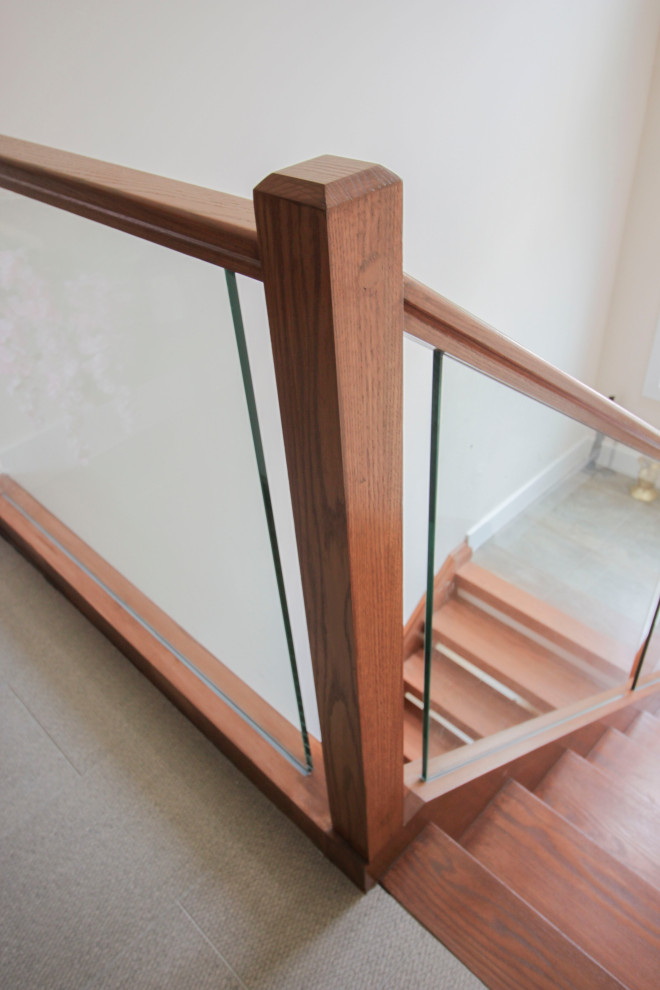 На фото: лестница на больцах, среднего размера в стиле модернизм с деревянными ступенями, стеклянными перилами и панелями на части стены с