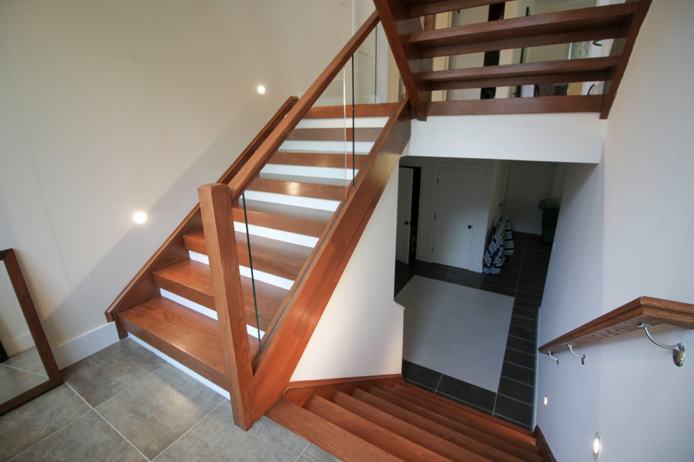 Diseño de escalera suspendida moderna de tamaño medio con escalones de madera, barandilla de vidrio y panelado