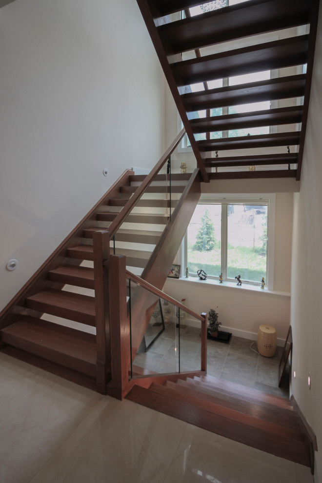 Foto de escalera suspendida minimalista de tamaño medio con escalones de madera, barandilla de vidrio y panelado