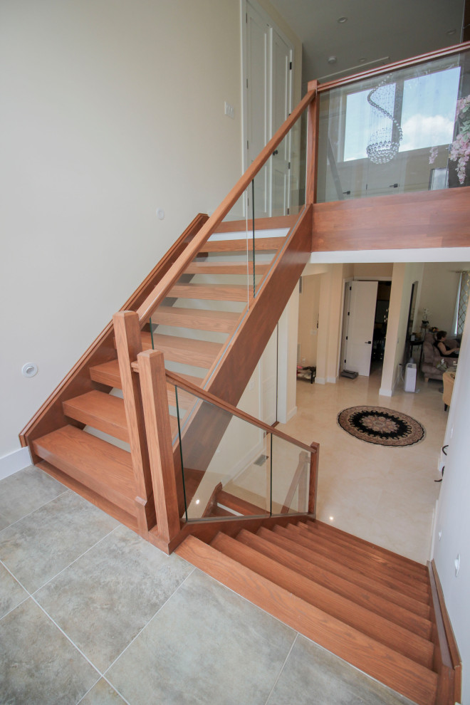 Réalisation d'un escalier flottant minimaliste de taille moyenne avec des marches en bois, un garde-corps en verre et du lambris.