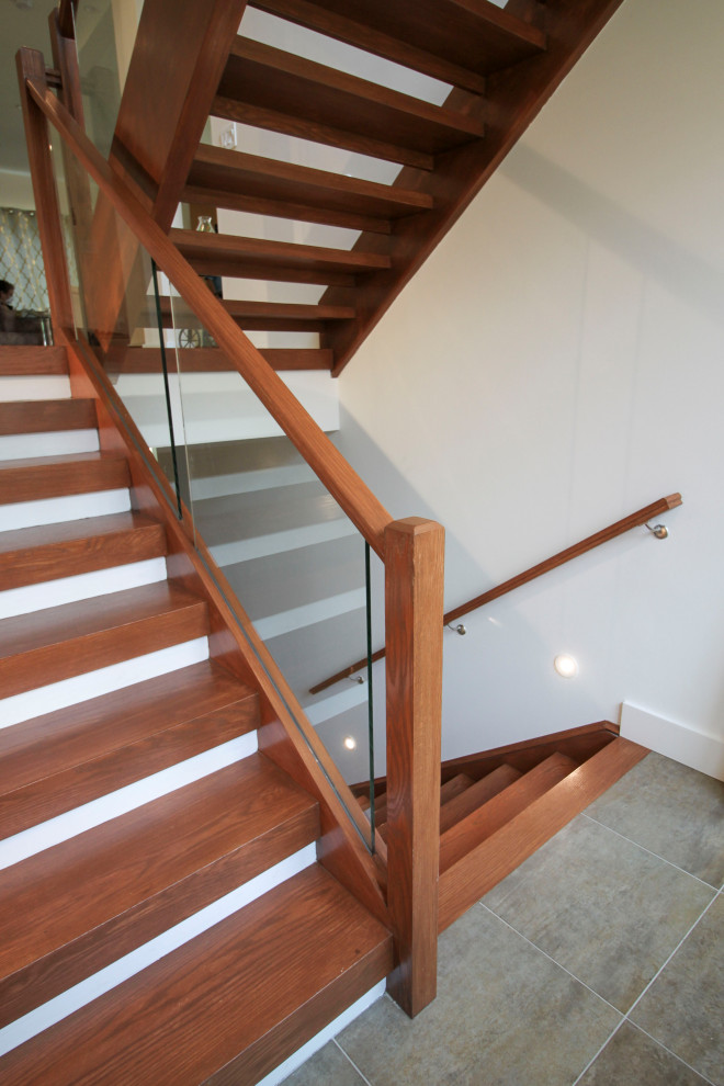 Aménagement d'un escalier flottant moderne de taille moyenne avec des marches en bois, un garde-corps en verre et du lambris.