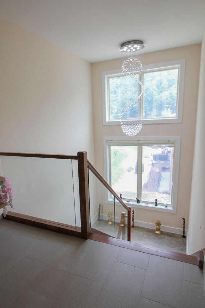 Пример оригинального дизайна: лестница на больцах, среднего размера в стиле модернизм с деревянными ступенями, стеклянными перилами и панелями на части стены