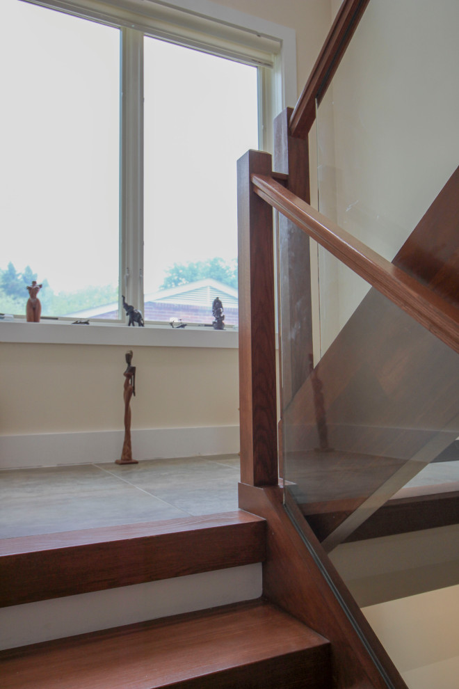 Foto di una scala sospesa minimalista di medie dimensioni con pedata in legno, parapetto in vetro e pannellatura