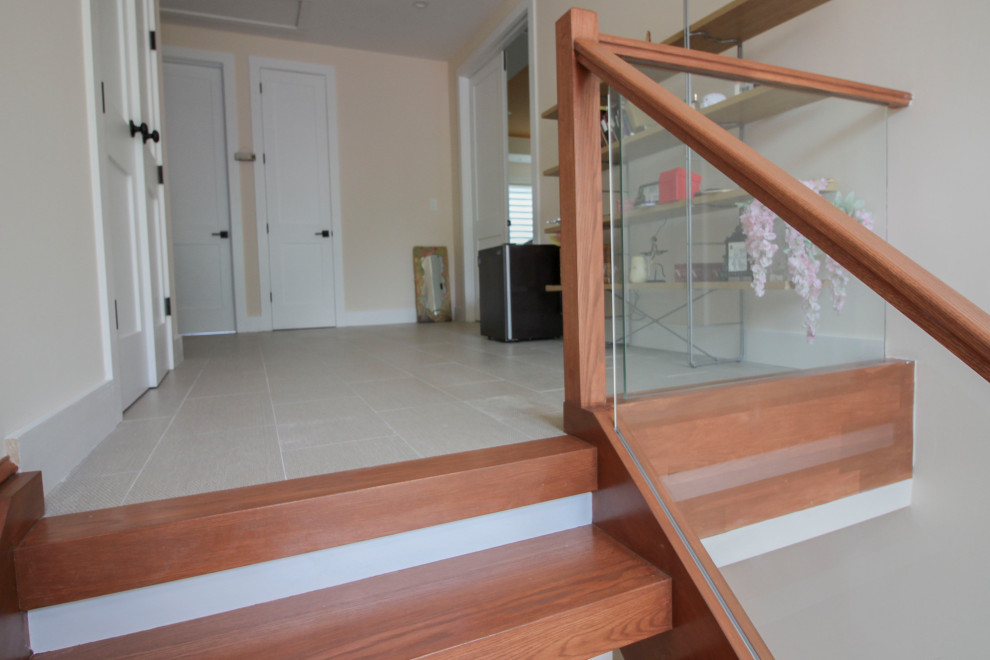 Cette image montre un escalier flottant minimaliste de taille moyenne avec des marches en bois, un garde-corps en verre et du lambris.