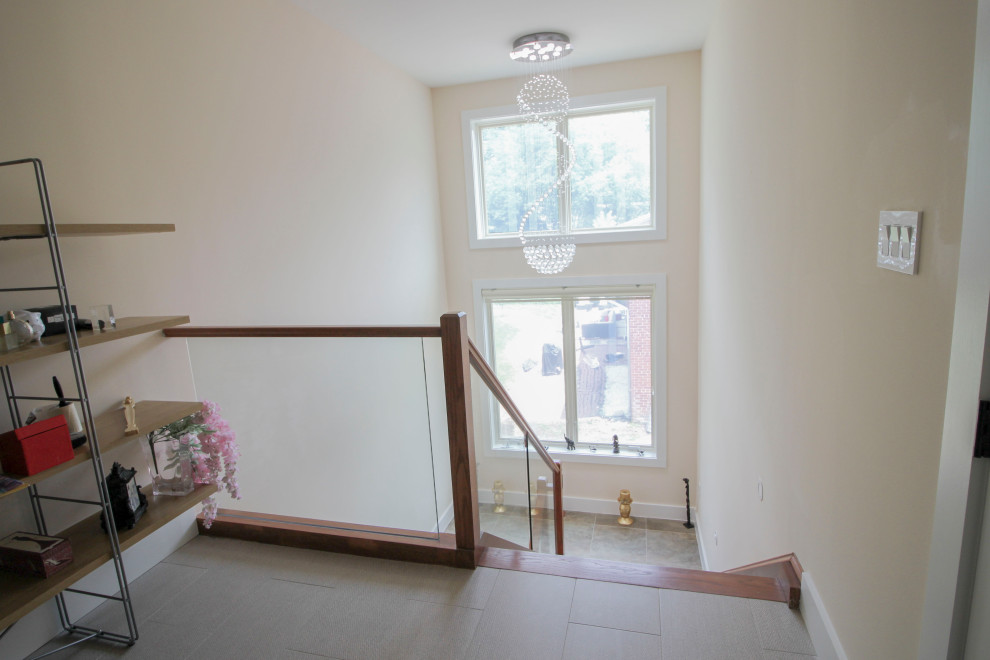 Diseño de escalera suspendida minimalista de tamaño medio con escalones de madera, barandilla de vidrio y panelado
