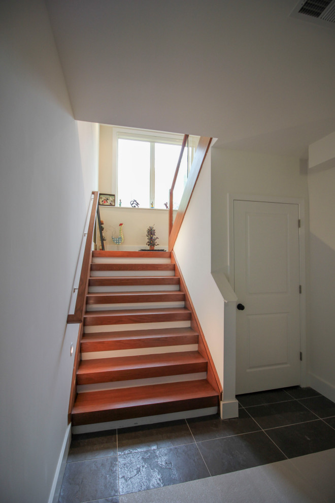 Пример оригинального дизайна: лестница на больцах, среднего размера в стиле модернизм с деревянными ступенями, стеклянными перилами и панелями на части стены